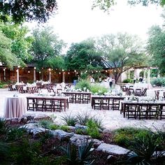 an outdoor dining area with tables, chairs and lights on the trees in the background