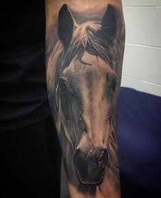 a black and grey horse tattoo on the arm