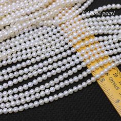 several strands of white pearls next to a measuring tape