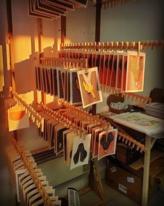 an art studio with clothes hanging on the line and pictures hung up to dry in front of them