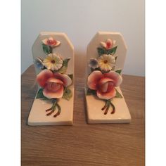 pair of ceramic bookends with flowers on them sitting on a table next to a wall