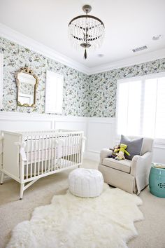 a baby's room with floral wallpaper and white furniture