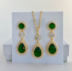 I've create this luxurious green emerald cubic zirconia bridal teardrop set in gold plated brass setting. This set includes: #Earrings feature a large teardrop with pear cut green emerald cubic zirconia center surrounded by tiny round zirconia crystals. Teardrop dangles from a earstud with brilliant cut red ruby cubic zirconia center and surrounded by tiny round zirconia crystals and a round cubic zirconia connector. Total length of the earring is 4.8 cms. #Necklace pendant features a large tear Green Cubic Zirconia Teardrop Pendant Jewelry, Gold Emerald Jewelry Sets For Formal Events, Gold Emerald Jewelry Sets For Formal Occasions, Emerald Drop Jewelry For Weddings, Green Drop Jewelry For Wedding, Emerald Drop Wedding Jewelry, Wedding Emerald Drop Jewelry, Wedding Drop Emerald Jewelry, Green Teardrop Jewelry Sets For Anniversary