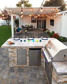 an outdoor kitchen with grill, sink and table