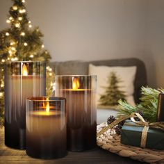 three candles sitting on top of a table next to a christmas tree