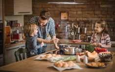 a man and two children are cooking in the kitchen