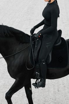 a woman riding on the back of a black horse