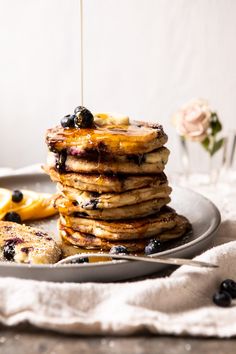 a stack of pancakes with blueberries and syrup being drizzled on top