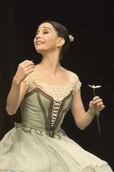 a woman in a green dress holding a flower