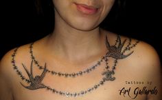 a woman with a bird tattoo on her chest is wearing a necklace that has birds attached to it