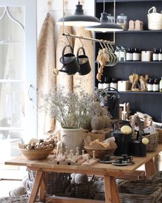 a wooden table topped with pots and pans next to shelves filled with bottles, jars and other items