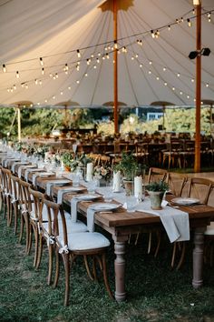 an outdoor tent with tables and chairs set up for dinner