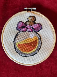 a cross stitched picture of a pot with a bow on it's head