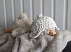 two crocheted teddy bears laying on top of a bed next to each other