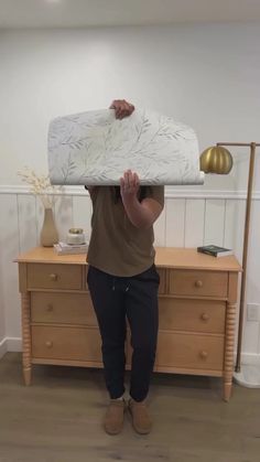 a woman holding up a mattress in front of her face