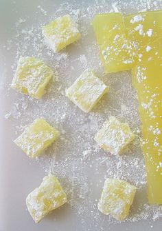 several pieces of yellow cake sitting on top of a white table covered in powdered sugar