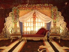 an elaborately decorated stage set up for a wedding ceremony with red and gold decor