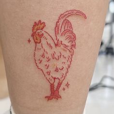 a rooster tattoo on the leg of a woman's thigh, with red ink