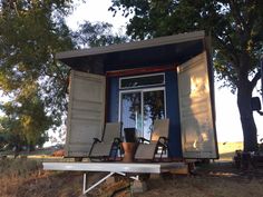 two chairs are sitting in the back of a tiny house that is built on stilts