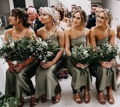 a group of women sitting next to each other in front of a crowd holding flowers