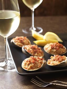 an image of some appetizers on a plate with wine and lemon wedges