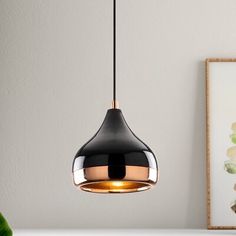 a black and gold pendant light hanging from a ceiling in a room with white walls