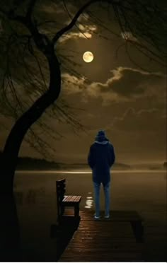 a man standing on a pier looking at the moon