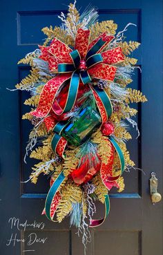 a christmas wreath on the front door of a house with red, green and gold decorations