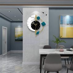 a clock on the wall above a table in a room with blue walls and grey chairs