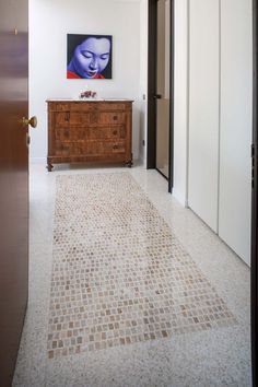 a room with a painting on the wall next to a dresser and door in it