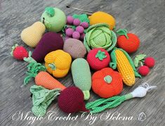 crocheted fruits and vegetables are arranged on the wooden floor, including carrots