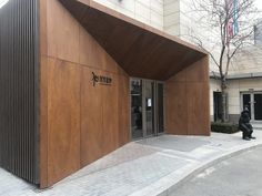 the entrance to an office building with wooden panels on it's sides and people walking by