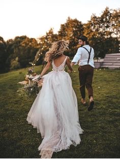 a bride and groom walking through the grass