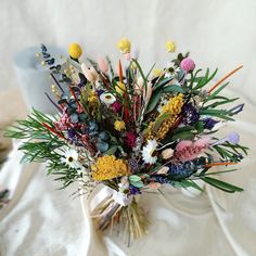 a vase filled with lots of colorful flowers on top of a white cloth covered table