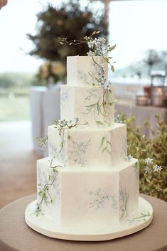 a white wedding cake with blue flowers and greenery