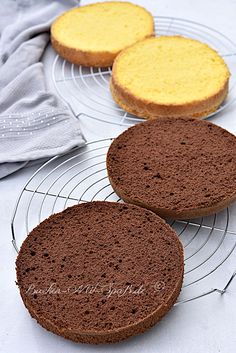 three cakes sitting on top of wire racks next to each other, one yellow and one brown