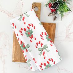 a wooden cutting board topped with candy canes next to a christmas napkin on top of a marble counter