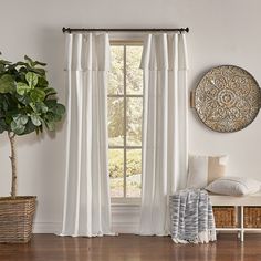 a living room with white curtains and a potted plant