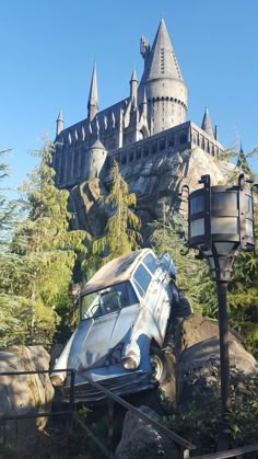 an old car that is sitting in front of a castle with its roof ripped off