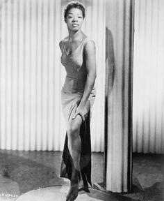 a black and white photo of a woman standing on a round object in front of curtains