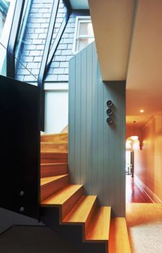 an open door leading to a hallway with wooden steps and windows on the side of it