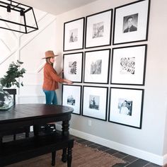 a woman standing in front of a wall with pictures on it