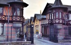 an old fashioned street with many houses on the sides and fenced in area next to it