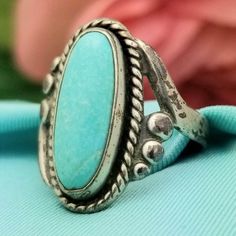 Southwestern-STYLE Sterling Silver Skinny Oval Turquoise Ring with Twisted Border Detail- Beautifully Crafted.  Made in the 1970s.  This True Vintage Piece features a Natural, Skinny Oval  Turquoise Gemstone that has Beautiful Marble Detail.  The Ring Itself is Made from Solid and Stamped  Sterling Silver with a Twisted Border Surrounding the Stone.  The Turquoise measures 15.5mm in Length 6mm Wide The Face of the Ring measures 13/16'' in Length 3/8'' Wide The Band measures 3.1mm in Width Split Antique Turquoise Ring With Patina, Bohemian Turquoise Concho Ring, Western-style Turquoise Ring With Patina, Turquoise Concho Ring As Gift, Turquoise Concho Ring As A Gift, Western Style Turquoise Ring Collectible, Turquoise Concho Ring For Gift, Southwestern Turquoise Rings With Patina, Bohemian Oval Turquoise Collectible Ring