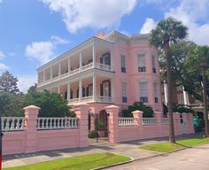 a pink house with white balconies and palm trees