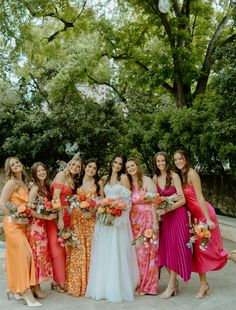 a group of women standing next to each other wearing dresses and holding bouquets in their hands