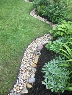 a garden with rocks and grass in the middle, along side a path that leads to a grassy area