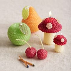 small crocheted mushrooms and raspberries are on the table next to each other