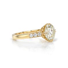 a yellow gold engagement ring with an oval cut diamond in the center and side stones