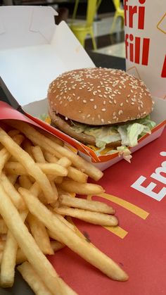 a hamburger and french fries are sitting on a table next to a box of fries